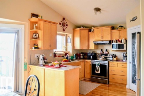 This kitchen features light-toned wooden cabinetry and hardwood flooring - 16832 79 Street Nw, Edmonton, AB - Indoor Photo Showing Kitchen