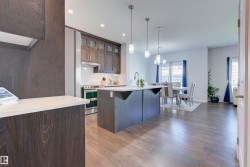 The kitchen features dark wood cabinetry, light countertops, and a central island with a sink - 