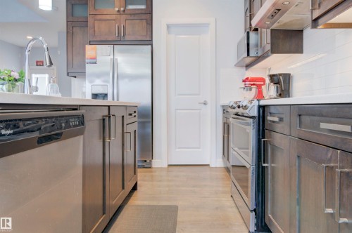 The kitchen features stainless steel appliances, including a dishwasher, oven, and refrigerator - 8452 Cushing Crest, Edmonton, AB - Indoor Photo Showing Kitchen