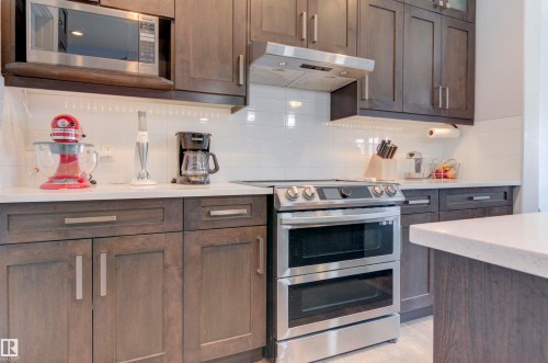 The kitchen features dark wood cabinetry, white subway tile backsplash, and light-colored countertops - 8452 Cushing Crest, Edmonton, AB - Indoor Photo Showing Kitchen With Upgraded Kitchen