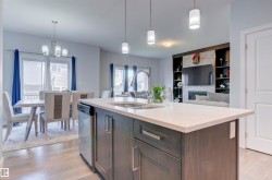 The kitchen features a center island with a sink, stainless steel appliances, and pendant lighting - 