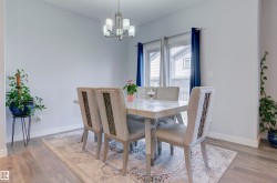 Dining area featuring hard surface flooring, a chandelier, and a large window with blue curtains - 