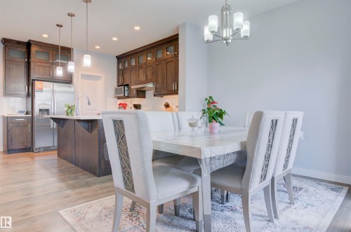 The property features an open-concept living area, showcasing a modern kitchen with dark wood cabinetry, stainless steel appliances, and a central island with a sink - 8452 Cushing Crest, Edmonton, AB - Indoor Photo Showing Dining Room