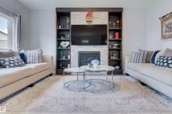 Living room featuring a fireplace with a stone facade, built-in shelving, and a large window providing natural light - 