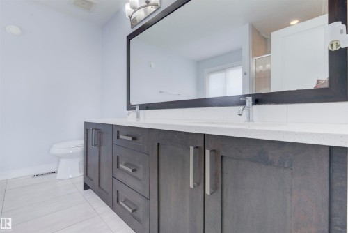 Bathroom featuring a dual vanity with a white countertop, two sinks, and chrome faucets - 8452 Cushing Crest, Edmonton, AB - Indoor Photo Showing Bathroom