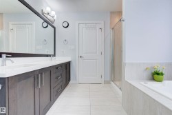 The bathroom features a double vanity with dark wood cabinetry, white countertops, and modern chrome faucets - 
