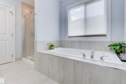 The bathroom features a built-in tub with chrome fixtures, a shower with a glass enclosure, and light-colored tiled flooring - 