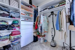 The property features a walk-in closet with built-in white shelving and drawers, providing extensive storage solutions - 