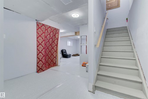 This space features light-colored walls and flooring, with a visible staircase including a handrail - 8452 Cushing Crest, Edmonton, AB - Indoor Photo Showing Other Room