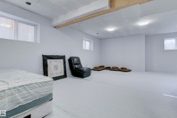 This spacious room features light-colored walls and flooring, with visible ceiling beams and recessed lighting fixtures - 
