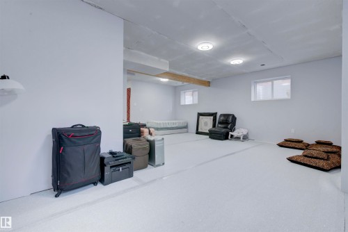 The property features a spacious room with light gray walls, recessed lighting, and windows providing natural light - 8452 Cushing Crest, Edmonton, AB - Indoor Photo Showing Basement