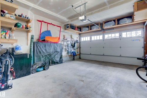 The property features a garage with a concrete floor, overhead storage shelves, and a garage door with windows - 8452 Cushing Crest, Edmonton, AB - Indoor Photo Showing Garage
