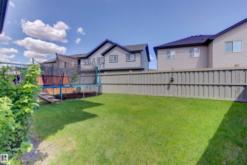 The property features a spacious backyard with a well-maintained lawn and a tall privacy fence - 8452 Cushing Crest, Edmonton, AB - Outdoor