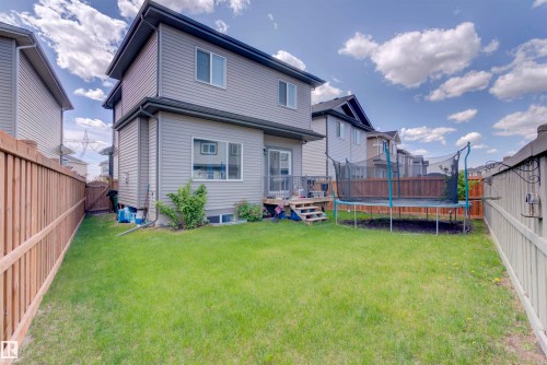 The property features a fenced backyard with a lawn and a deck, providing outdoor living space - 8452 Cushing Crest, Edmonton, AB - Outdoor With Deck Patio Veranda With Exterior
