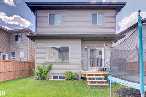 The property features a well-maintained lawn, a wooden fence, and a deck with stairs leading to the yard - 8452 Cushing Crest, Edmonton, AB - Outdoor With Deck Patio Veranda With Exterior