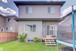 The property features a well-maintained lawn, a wooden fence, and a deck with stairs leading to the yard - 