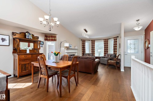This open-concept interior features hardwood floors throughout, a vaulted ceiling, and a prominent front door with decorative glass - 14 920 119 Street, Edmonton, AB - Indoor