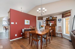 The dining area features hardwood floors, a vaulted ceiling, and an elegant chandelier - 