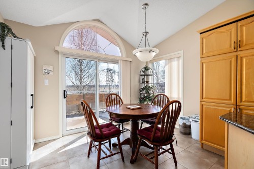 This bright dining area features a vaulted ceiling, a hanging light fixture, and tile flooring - 14 920 119 Street, Edmonton, AB - Indoor Photo Showing Dining Room
