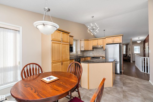 The property features a kitchen with light-toned wooden cabinetry, dark granite countertops, and stainless steel appliances - 14 920 119 Street, Edmonton, AB - Indoor