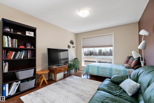 This room features hardwood flooring, a large window providing natural light, and a ceiling-mounted light fixture - 14 920 119 Street, Edmonton, AB - Indoor