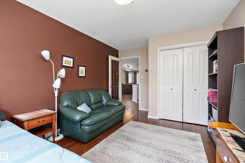 This room features warm-toned walls, hardwood style flooring, and a door with frosted glass panels - 14 920 119 Street, Edmonton, AB - Indoor Photo Showing Bedroom