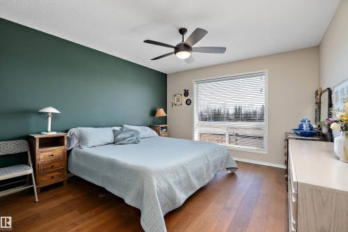 This room features hardwood flooring, a ceiling fan with integrated lighting, and a large window with horizontal blinds - 14 920 119 Street, Edmonton, AB - Indoor Photo Showing Bedroom