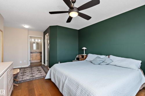 This bedroom features hardwood floors, a ceiling fan with integrated lighting, and a dark green accent wall - 14 920 119 Street, Edmonton, AB - Indoor Photo Showing Bedroom