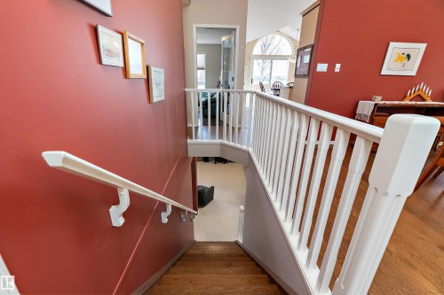 Staircase with hardwood treads, white balusters, and a white handrail, complemented by a vibrant red wall - 14 920 119 Street, Edmonton, AB - Indoor Photo Showing Other Room