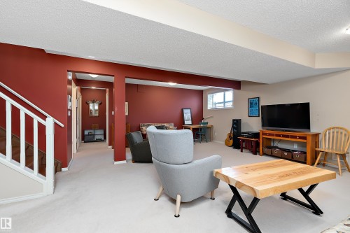 Spacious living area featuring carpeting, warm red accent walls, and white trim - 14 920 119 Street, Edmonton, AB - Indoor