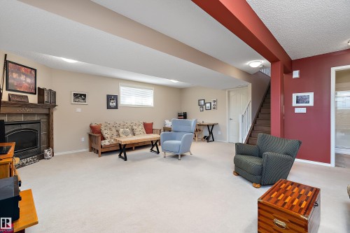 Spacious living area featuring light-colored carpeting, a fireplace with a wood mantle, and a window providing natural light - 14 920 119 Street, Edmonton, AB - Indoor With Fireplace