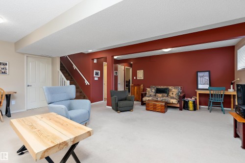 The living area features light-colored carpeting, a staircase with white railings, and walls painted in a deep red hue - 14 920 119 Street, Edmonton, AB - Indoor