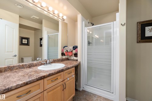 Bathroom featuring a vanity with a countertop, a single sink, and light wood cabinetry - 14 920 119 Street, Edmonton, AB - Indoor Photo Showing Bathroom