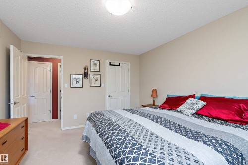This bedroom features light neutral-toned walls, a white textured ceiling, and light-colored carpeting - 14 920 119 Street, Edmonton, AB - Indoor Photo Showing Bedroom