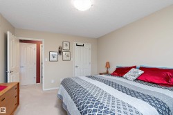This bedroom features light neutral-toned walls, a white textured ceiling, and light-colored carpeting - 