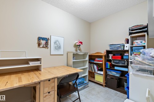 This versatile room features neutral-toned walls, a drop-leaf wooden desk, and a tiled floor - 14 920 119 Street, Edmonton, AB - Indoor
