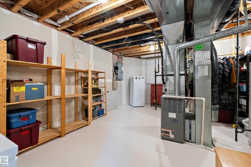 The property features an unfinished basement with exposed ceiling joists and ductwork, a white water heater, and a furnace - 14 920 119 Street, Edmonton, AB - Indoor Photo Showing Basement