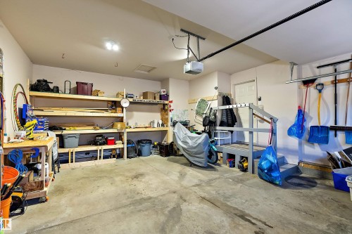 The property features a garage with concrete flooring, overhead lighting, and built-in wooden shelving for storage - 14 920 119 Street, Edmonton, AB - Indoor Photo Showing Garage