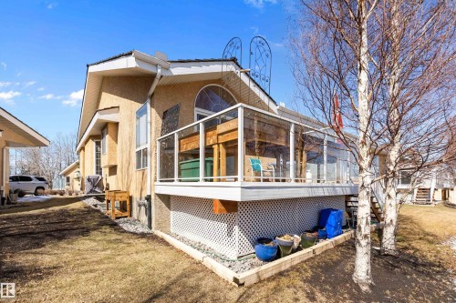 The property features a stucco exterior, a sunroom with clear panels, and a ground-level area with decorative lattice skirting - 14 920 119 Street, Edmonton, AB - Outdoor