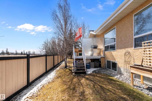 The property features an exterior with textured siding, large windows, and a raised deck with stairs - 14 920 119 Street, Edmonton, AB - Outdoor