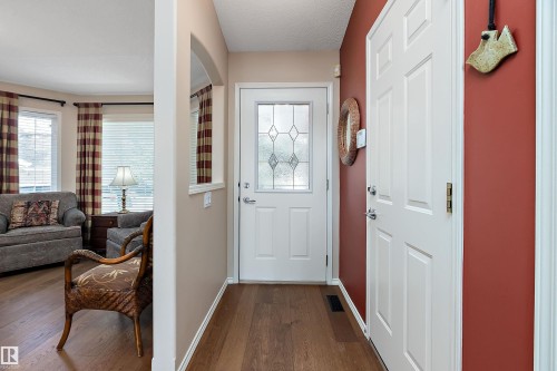 The entryway features hardwood flooring, a white front door with decorative glass, and a warm red accent wall - 14 920 119 Street, Edmonton, AB - Indoor