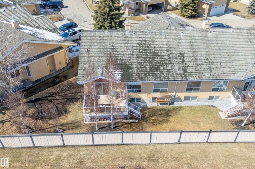 The property features an extensive backyard with a lawn, a deck, a patio area with gravel, and a fence - 14 920 119 Street, Edmonton, AB - Outdoor