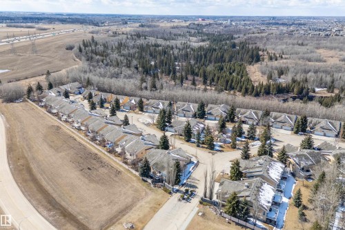 Aerial view showcasing a community of homes with sloped roofs and attached garages, set against a backdrop of extensive tree coverage - 14 920 119 Street, Edmonton, AB - Outdoor With View