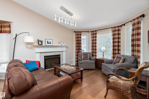 Living room featuring hardwood floors, a fireplace with a mantel, and large windows providing natural light - 14 920 119 Street, Edmonton, AB - Indoor Photo Showing Living Room With Fireplace