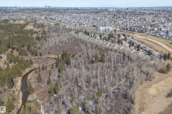 Aerial view of the surrounding area featuring a winding river, dense woodland, and residential properties - 