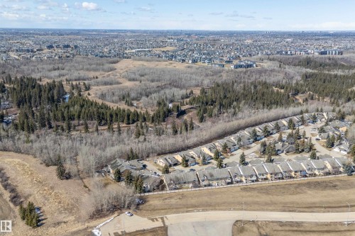 Aerial view showcasing the residential community, characterized by rows of properties with pitched roofs, and surrounded by extensive natural landscapes including forests and open fields - 14 920 119 Street, Edmonton, AB - Outdoor With View