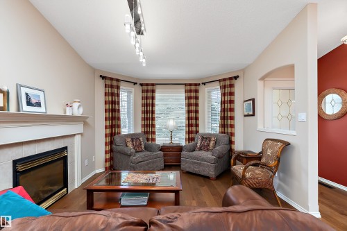 Living room featuring hardwood floors, a fireplace with a tiled surround and mantel, and a bay window - 14 920 119 Street, Edmonton, AB - Indoor Photo Showing Living Room With Fireplace