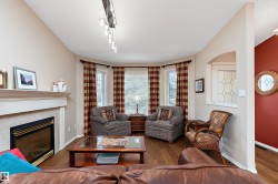 Living room featuring hardwood floors, a fireplace with a tiled surround and mantel, and a bay window - 