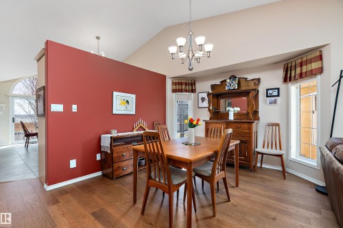 The dining area features hardwood floors, a vaulted ceiling, and an elegant chandelier - 14 920 119 Street, Edmonton, AB - Indoor Photo Showing Dining Room