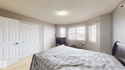 This room features light-colored carpeting, white paneled doors, and a bay window with blinds - 5929 8 Avenue, Edmonton, AB - Indoor Photo Showing Bedroom